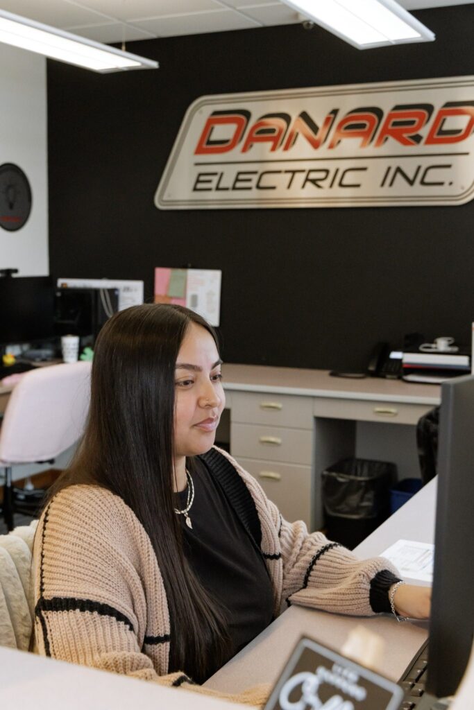 Office staff member working at a computer inside the Danard Electric Inc. office.